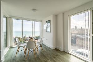 ein Esszimmer mit einem Tisch und Stühlen sowie großen Fenstern in der Unterkunft Seaview West Coast in Bournemouth