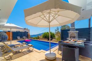 eine Terrasse mit einem Sonnenschirm und einem Pool in der Unterkunft Kalkan Halal villa in Kaş