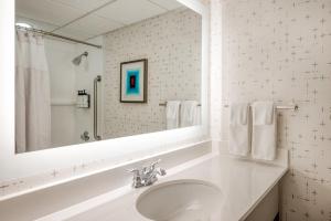 La salle de bains blanche est pourvue d'un lavabo et d'un miroir. dans l'établissement Crowne Plaza Indianapolis-Airport, an IHG Hotel, à Indianapolis