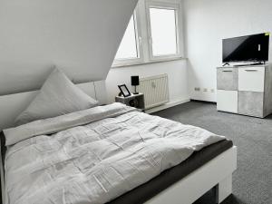 um quarto com uma cama branca e uma televisão em Ferienwohnung Flaming House Bitterfeld em Bitterfeld