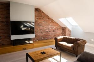 a living room with a couch and a tv and a brick wall at Principia Suites in León