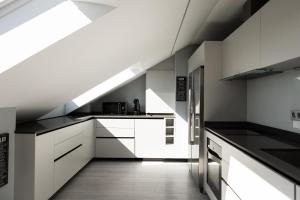 a kitchen with white cabinets and black counter tops at Principia Suites in León