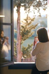 Une femme qui regarde par une fenêtre le reflet d'une femme dans l'établissement Sourediko, à Kambos