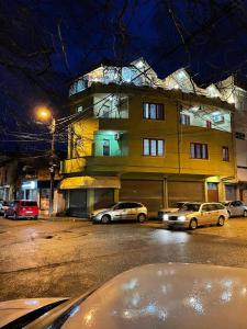 two cars parked in front of a building at night at Maison Centre in Shkodër