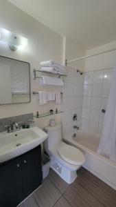 a bathroom with a toilet and a sink and a tub at Lord Nelson Motel in Kingston