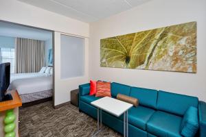 シャンバーグにあるSpringhill Suites by Marriott Chicago Schaumburg/Woodfield Mallのリビングルーム(青いソファ、ベッド付)