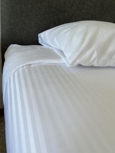 an unmade bed with white sheets and pillows at Homeport Motel in Lunenburg