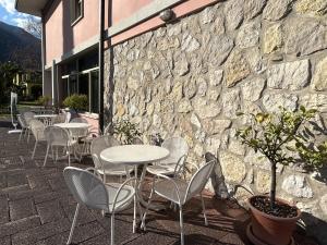 un groupe de tables et de chaises devant un mur en pierre dans l'établissement Hotel Diana, à Riva del Garda