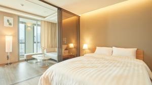 Un dormitorio con una gran cama blanca y una ventana en Elbon The Stay, en Busan