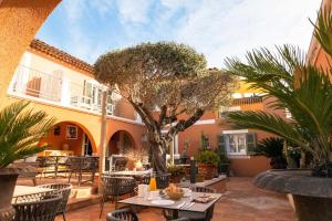 un patio con mesas, sillas y un árbol en Le Mouillage, en Saint-Tropez