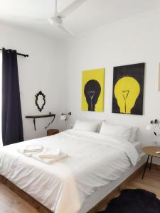 una camera da letto con un letto bianco con quattro immagini sul muro di Minimal apartment by the beach a Korinthos