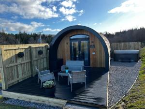 - un kiosque avec une table et des chaises sur une terrasse dans l'établissement Highland Premier Glamping Pods, à Beauly