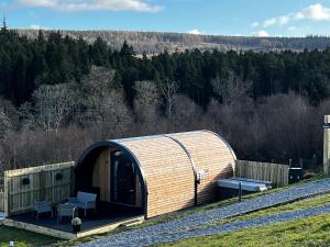 un bâtiment en bois avec un banc dans un champ dans l'établissement Highland Premier Glamping Pods, à Beauly