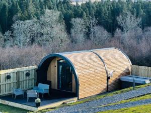 un petit bâtiment en bois avec une table et deux bancs dans l'établissement Highland Premier Glamping Pods, à Beauly