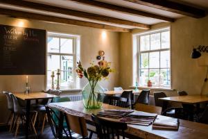 een restaurant met tafels en stoelen en een vaas met bloemen bij Bij Hen op Ameland in Hollum