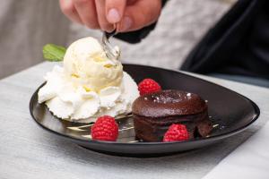 een persoon die een stuk chocoladetaart en aardbeien eet bij Bij Hen op Ameland in Hollum