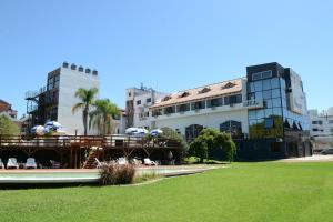 un bâtiment avec une terrasse et une pelouse en face de celui-ci dans l'établissement Hotel El Condado, à Villa Carlos Paz