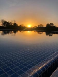 a swimming pool with the sunset in the background at Quinta das Donas in Anadia