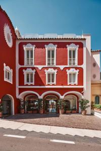 ein rotes Gebäude mit weißen Fenstern und Topfpflanzen in der Unterkunft Le Sirenuse in Positano