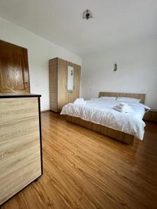 een slaapkamer met een groot bed en een houten vloer bij Casa Rus in Leordina