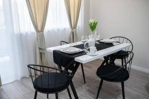 a dining room table with black chairs and a white table at TEILOR Apartments 5 in Floreşti