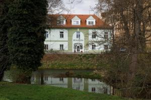 una grande casa bianca con un laghetto davanti di Litvan SUNSET Apartments a České Budějovice