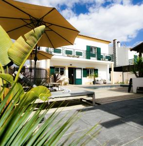 a house with a patio with a bench and an umbrella at Casa Idalia Boutique Hotel in Comporta