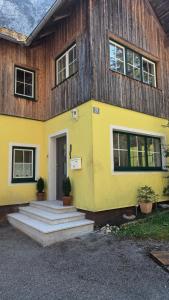 une maison jaune avec des escaliers devant elle dans l'établissement Haus Waldbach, à Hallstatt