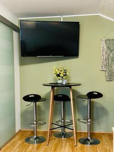 a table with four stools and a television on a wall at Apartment Buga Bilje in Bilje