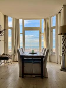 una sala da pranzo con tavolo, sedie e finestre di Sea view Scheveningen a Scheveningen