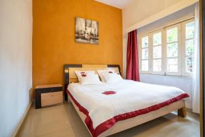 een slaapkamer met een groot bed met oranje muren bij Aparthotel Madeleine in Antananarivo