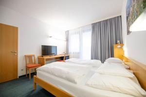 una camera d'albergo con 2 letti e una scrivania di Parkhotel Hirschwang a Reichenau