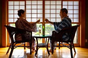 een man en vrouw aan een tafel met wijnglazen bij 由布の里 旅荘 牧場の家 Ryoso Makibanoie in Yufu