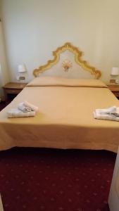 1 dormitorio con 1 cama grande y 2 toallas. en Hotel Posta R.T.A., en Madonna di Campiglio