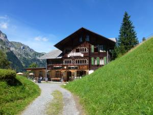 ein großes Holzhaus auf einem Hügel mit einer Feldstraße in der Unterkunft Hotel Waldrand in Kiental