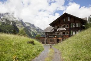 ein großes Holzgebäude auf einem Hügel mit Bergen im Hintergrund in der Unterkunft Hotel Waldrand in Kiental