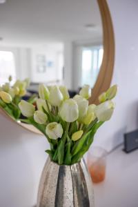 eine Vase voller weißer Blumen vor einem Spiegel in der Unterkunft Seaview West Coast in Bournemouth