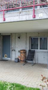 une chaise assise devant un bâtiment avec fenêtre dans l'établissement Studio CHic, à Niederweningen