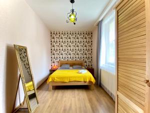 1 dormitorio con cama amarilla y espejo en Eco Forest Villa, en Tiflis