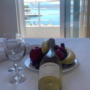 una bottiglia di vino seduta su un tavolo con un piatto di frutta di Zero Zero Apartments Sarande a Sarandë