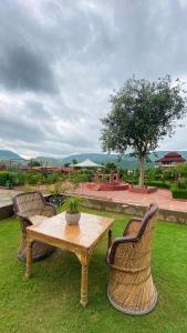 a wooden table with two chairs and a potted plant at DESI THATH RESORT in Alwar