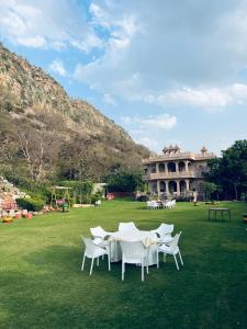 a group of white chairs and a table in a field at Namanbagh in Alwar