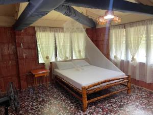 - une chambre avec un lit dans une pièce dotée de fenêtres dans l'établissement Borbon's Treehouse By the Sea, à Mambajao