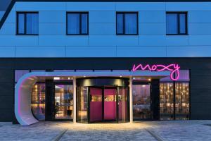 un edificio con una señal rosa en la parte delantera. en Moxy Frankfurt Airport Kelsterbach, en Kelsterbach