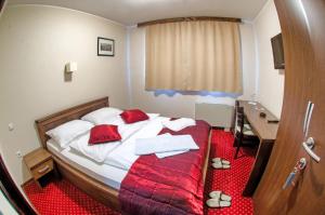 een slaapkamer met een bed met rode lakens en een bureau bij Hotel Konak Konjic in Konjic