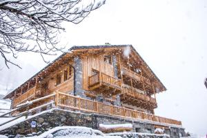 una cabaña de madera en la nieve con nieve en Ellex Eco Hotel, en Gressoney-la-Trinité