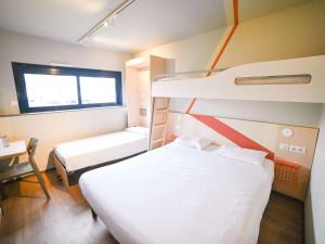 a hospital room with two beds and a desk at ibis budget Site du Futuroscope in Chasseneuil-du-Poitou