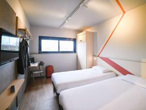 a small room with two beds and a desk at ibis budget Site du Futuroscope in Chasseneuil-du-Poitou