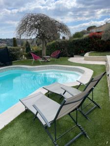 een zwembad met twee stoelen en een tafel ernaast bij Gîte des Restanques in Grasse