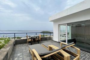 uma varanda com uma mesa e cadeiras e o oceano em StayVista at Tarika's Seascapes with Pool & Home Theatre em Dabolim